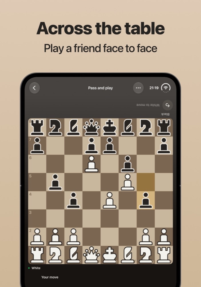 Across the table: a chess board on an unfolded iPhone Duo in pass and play, with Black's status line printed upside down at the top for the player sitting opposite